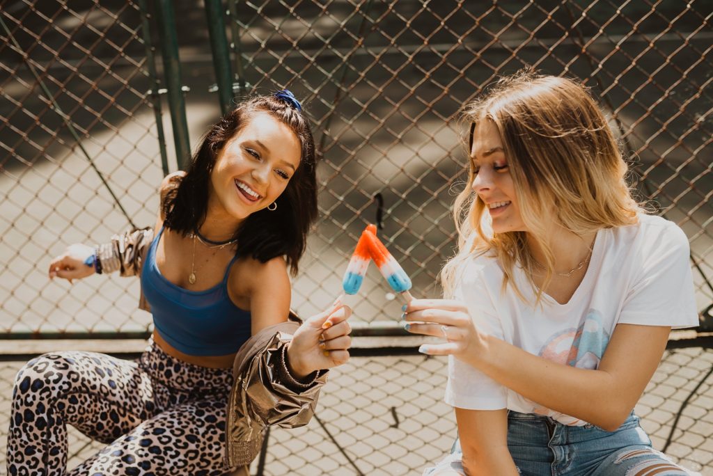 two girls cheersing with popsicles 